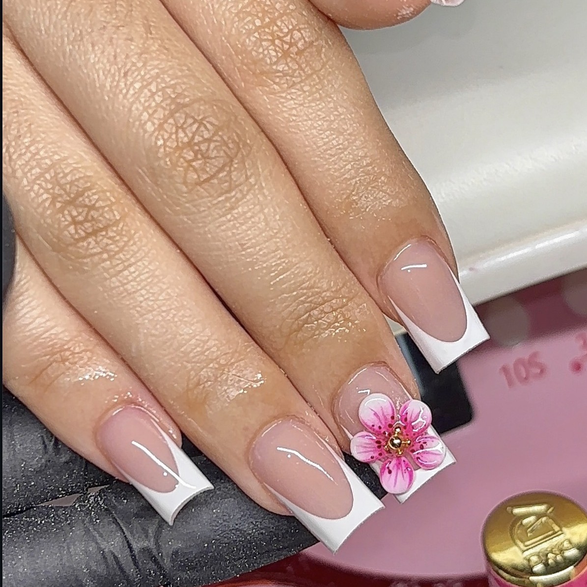 Short square Gel-X nails featuring a soft pink nude base, white French tips, and a pink floral accent nail by n4ilsbybellaa
